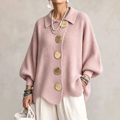 Woman wearing dusty pink button-down knit cardigan with gold buttons, pearl necklace, and white woven bag